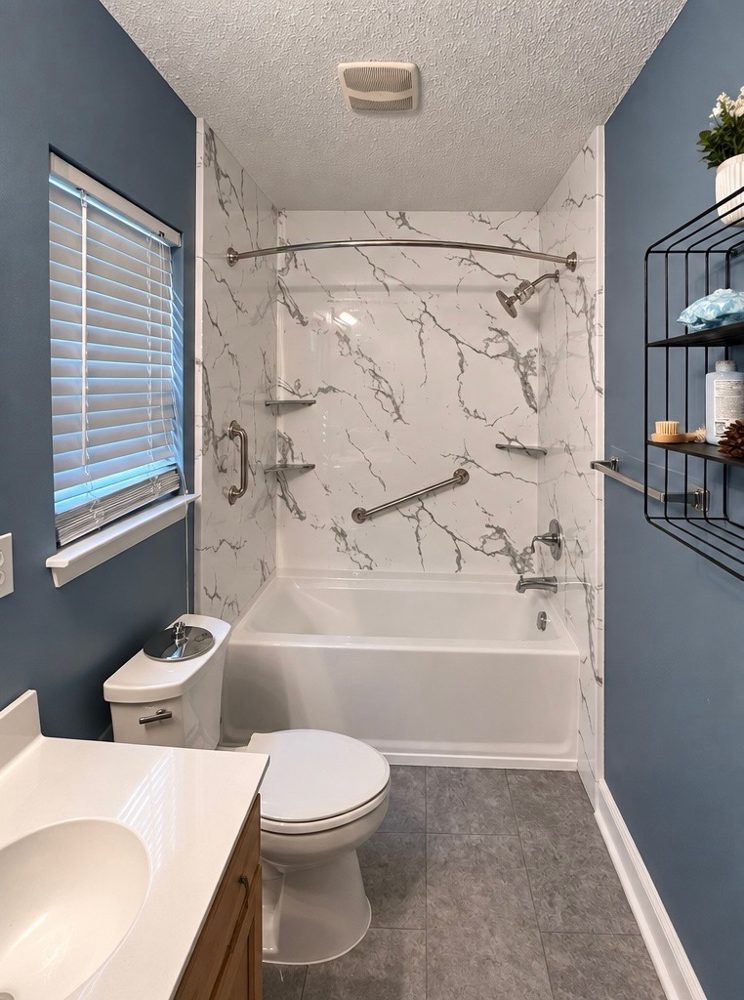 Small remodeled bathroom in a Charlotte-area home with marble-look acrylic walls