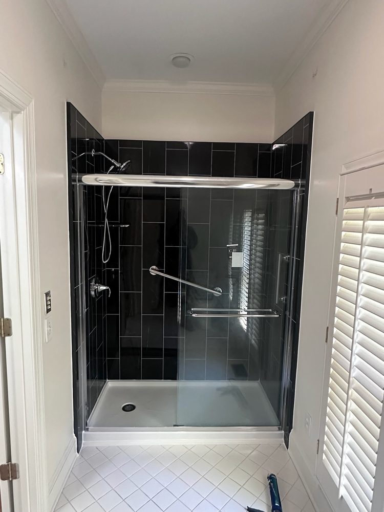 Walk-in shower with dark tile-look walls and a sliding glass door