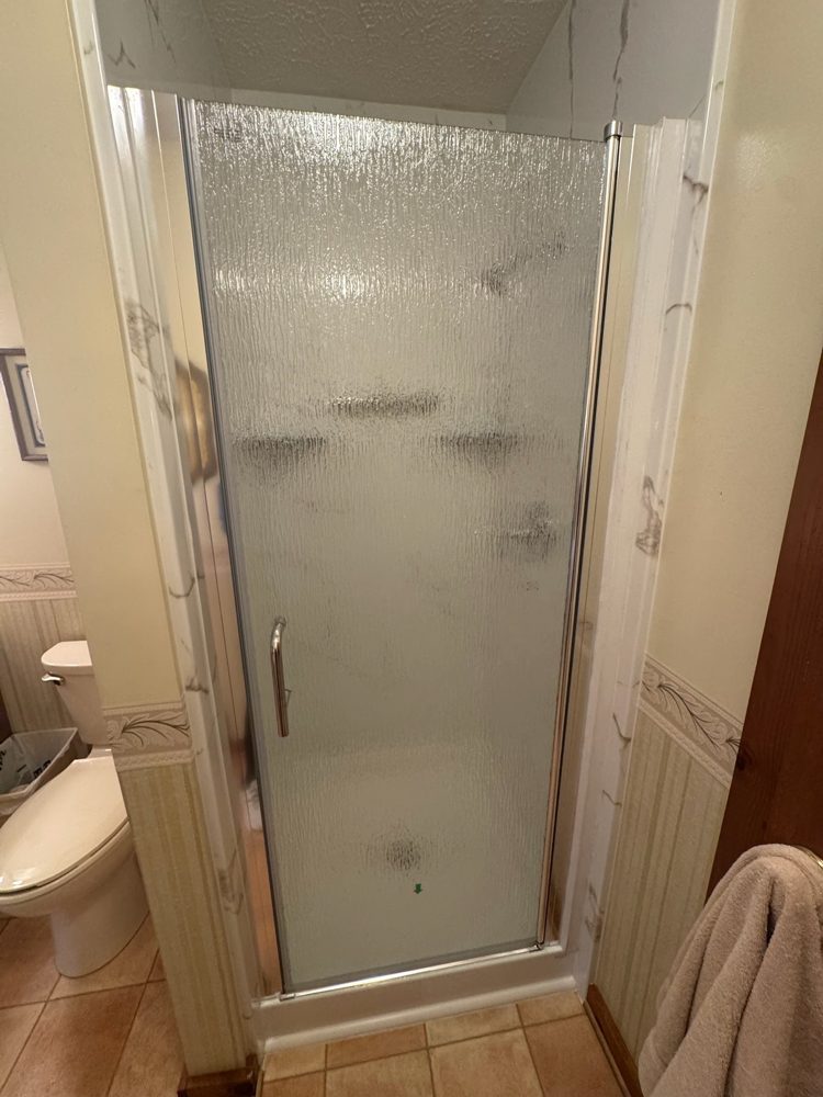 Finished walk-in shower with white marble-look acrylic walls and a frosted glass door in a Charlotte-area home