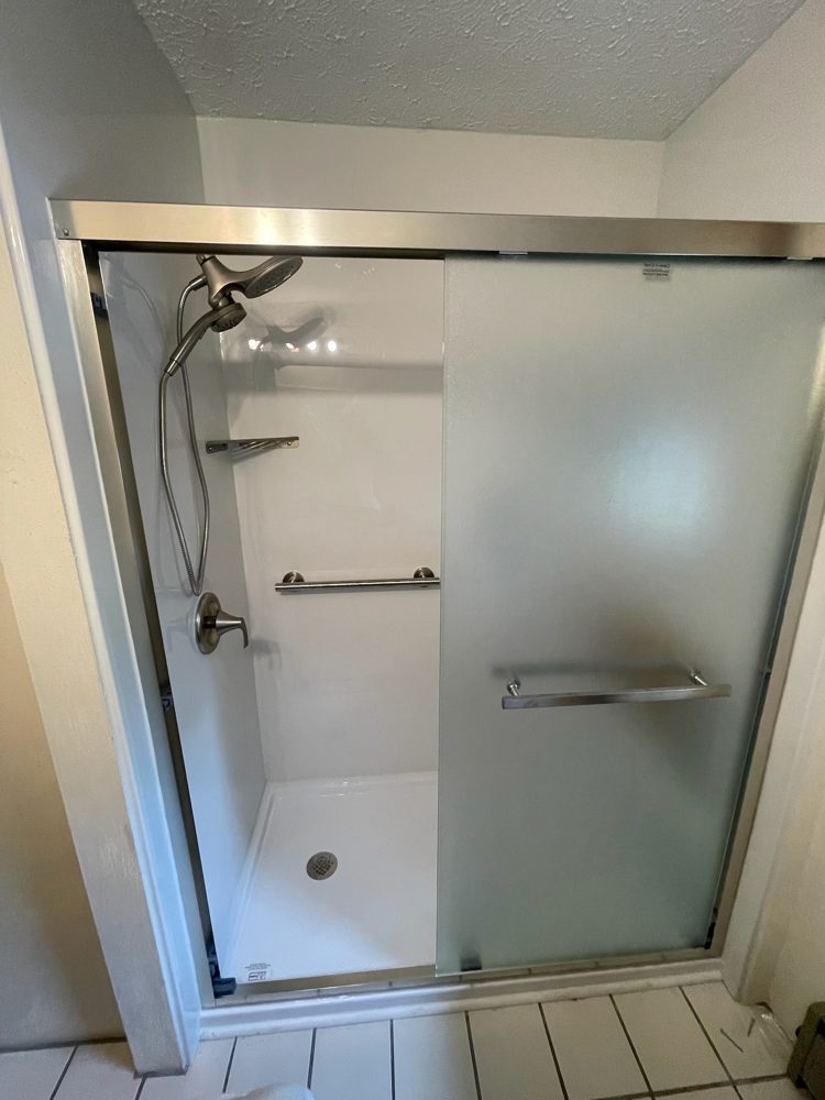 Walk-in shower with sliding glass door, grab bar and acrylic walls
