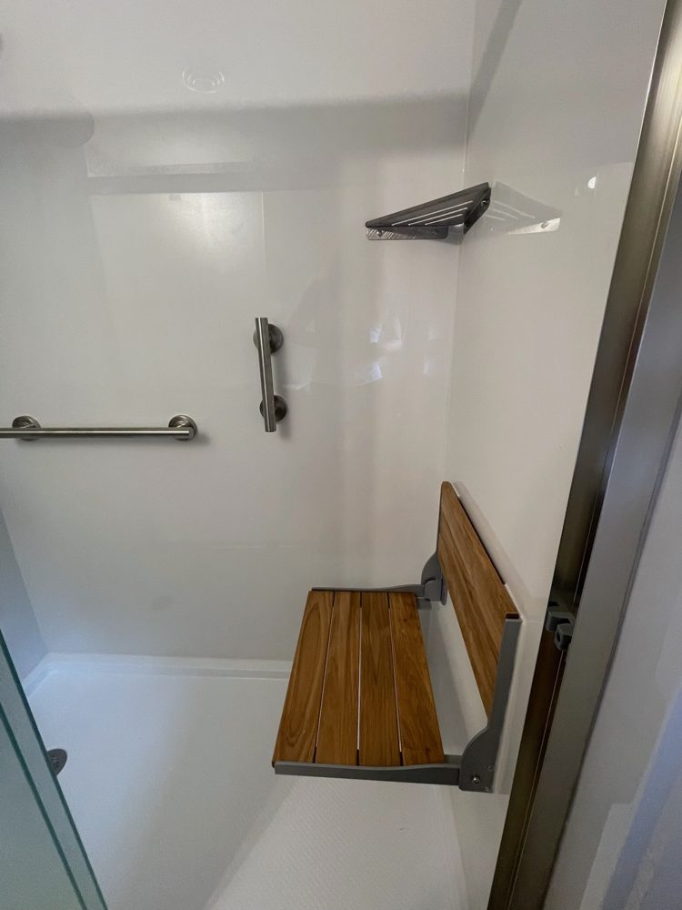 Walk-in shower with a fold-down teak seat and grab bar